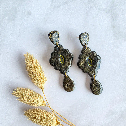 Unieke lange zwarte bloemvormige oorbel met gouden accenten